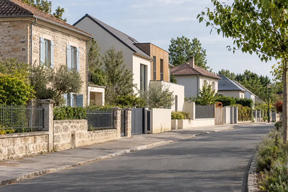Maisons aux toitures et clôtures différentes dans une rue